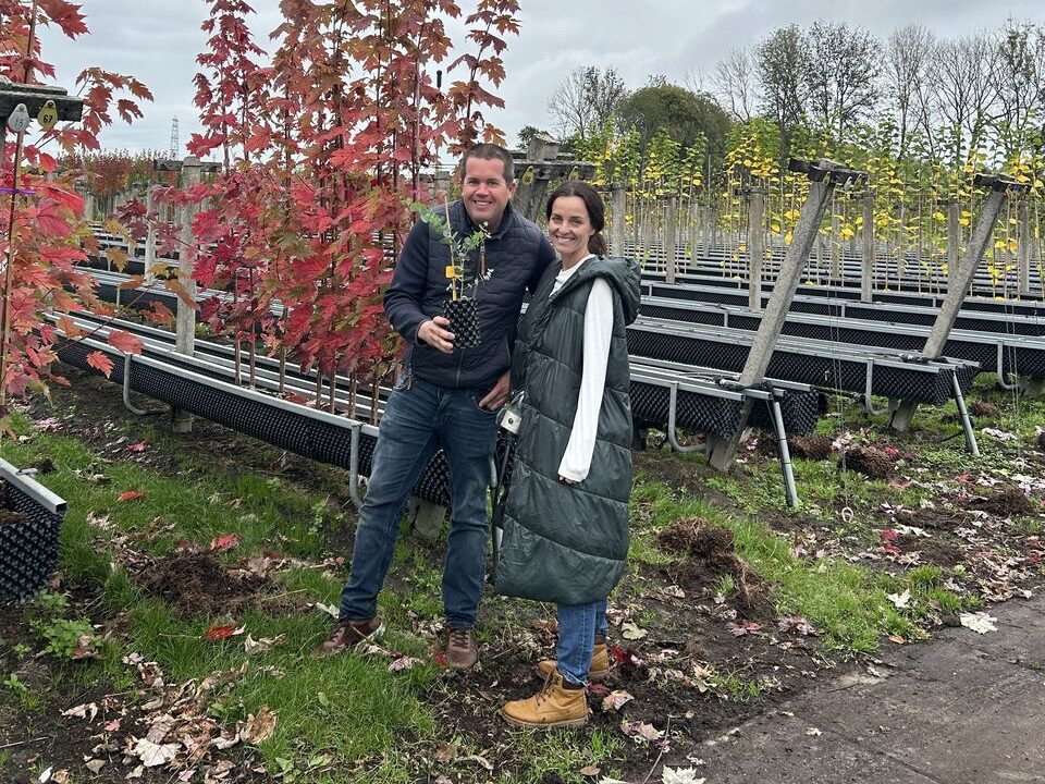 Dva lidé stojí v zahradnictví mezi stromky.